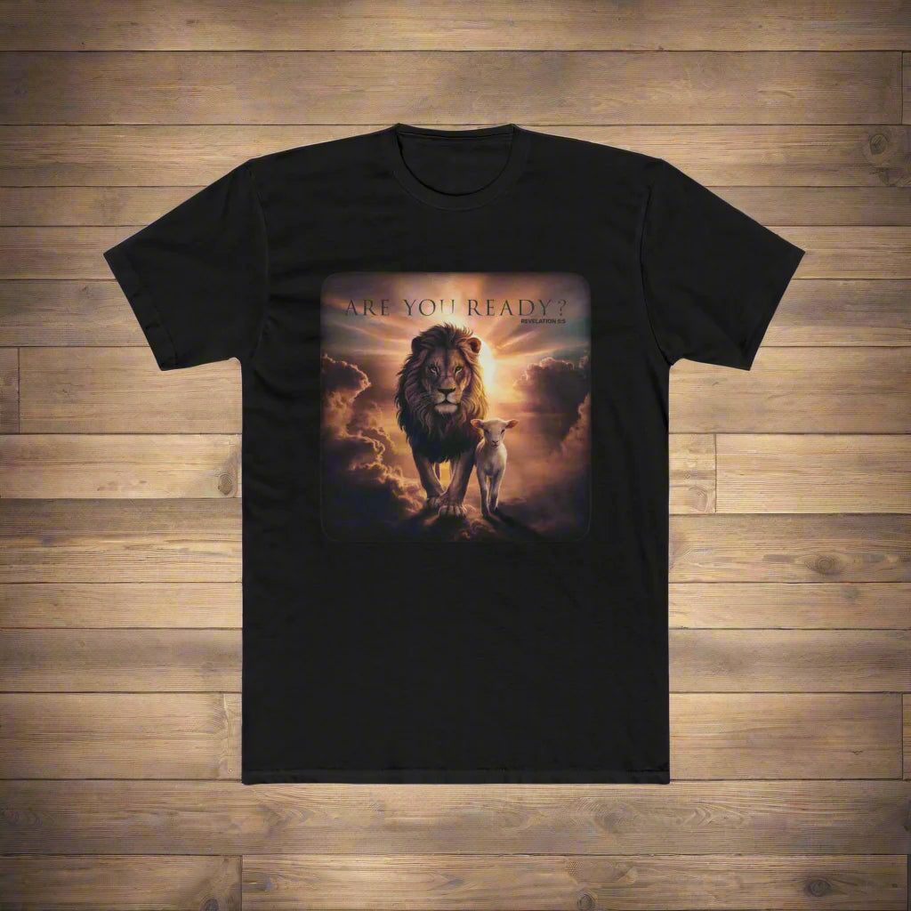A black t-shirt is displayed on a wooden floor, featuring a vivid graphic of a majestic lion and a lamb standing together under dramatic, glowing clouds. Above the image, the text reads "ARE YOU READY?" with "Revelation 5:5" written underneath. The design evokes themes of strength, peace, and biblical prophecy.